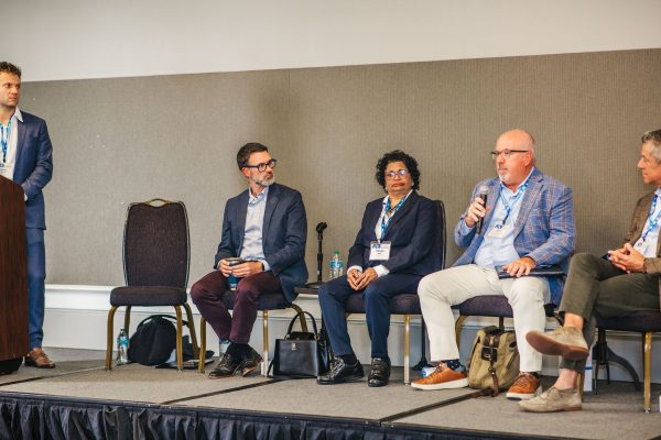 A panel discussion featuring four speakers seated on a stage.