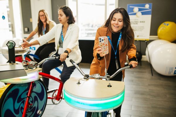 Three women are engaged in an interactive exhibit featuring bicycles.