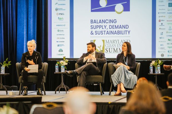 A panel discussion at the Maryland Clean Energy Summit featuring three speakers seated on stage.