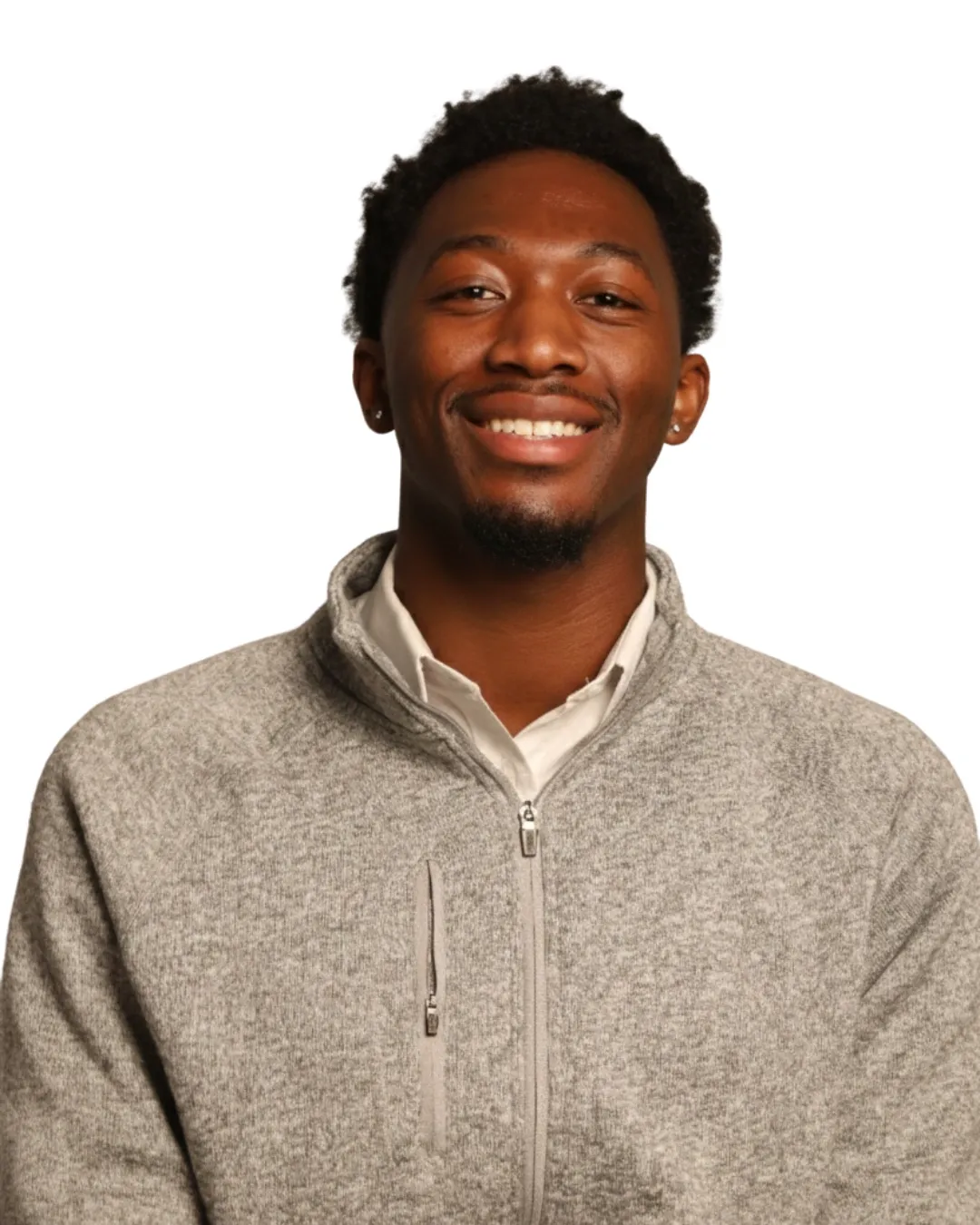 A young man with short, curly hair smiles while wearing a light gray zip-up sweater over a white shirt. The background is plain white