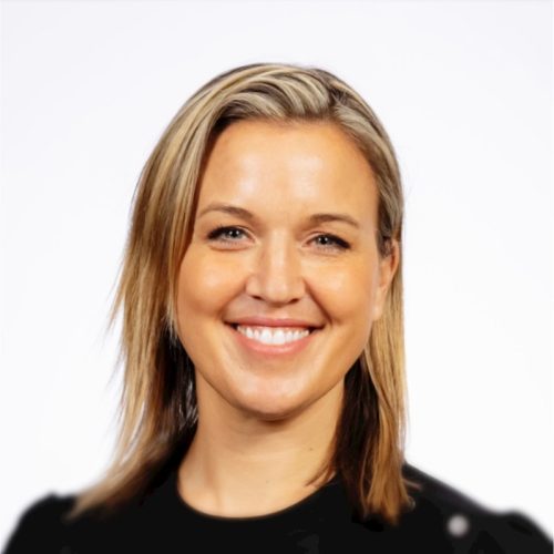 A woman with shoulder-length blonde hair and a bright smile is facing the camera. She is wearing a black shirt and has a neutral background